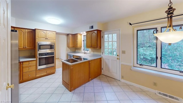 kitchen with pendant lighting, appliances with stainless steel finishes, and kitchen peninsula