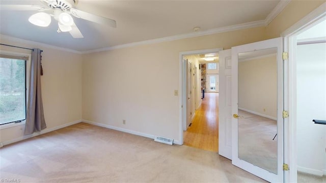 spare room featuring ceiling fan, light colored carpet, and ornamental molding