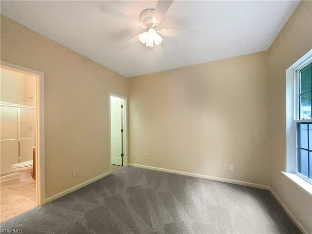 unfurnished room featuring a wealth of natural light, dark colored carpet, and ceiling fan