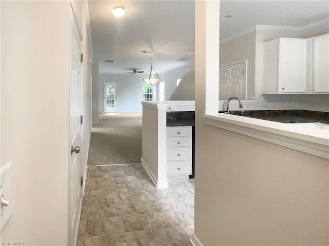 interior space featuring white cabinets, pendant lighting, ceiling fan, sink, and light carpet