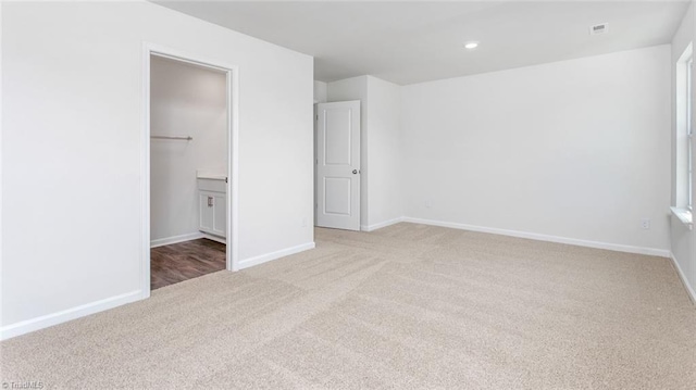 unfurnished bedroom with a spacious closet, a closet, and light carpet