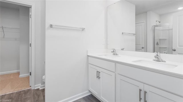 bathroom with toilet, vanity, wood-type flooring, and walk in shower