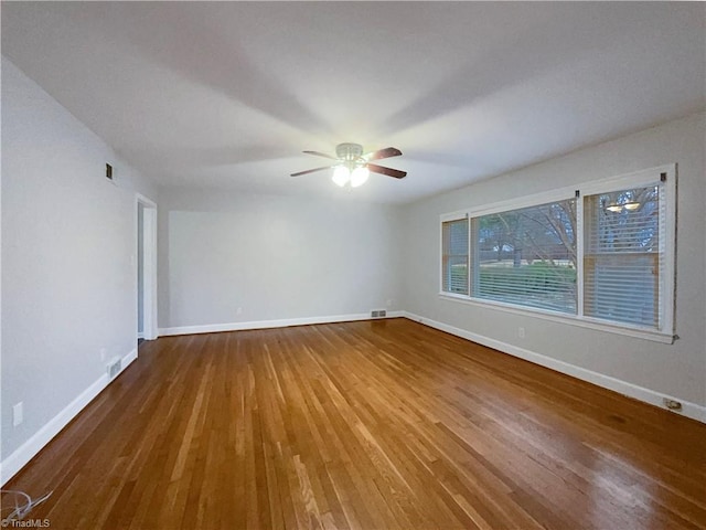 unfurnished room featuring ceiling fan, wood finished floors, visible vents, and baseboards