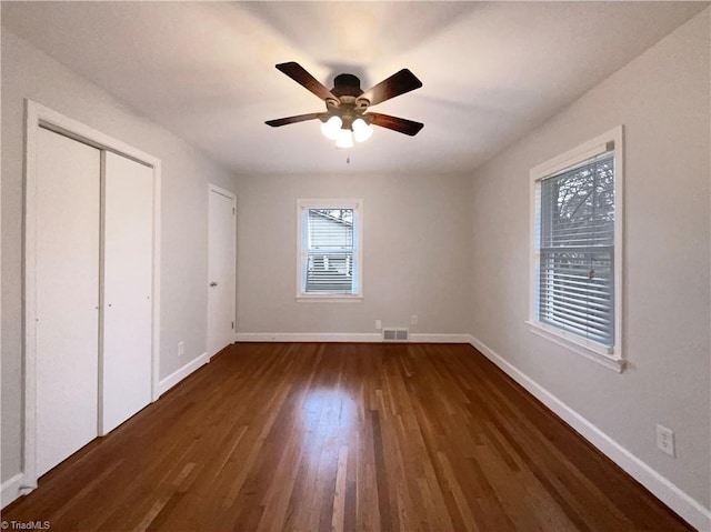 unfurnished bedroom featuring ceiling fan, dark wood-style flooring, visible vents, and baseboards