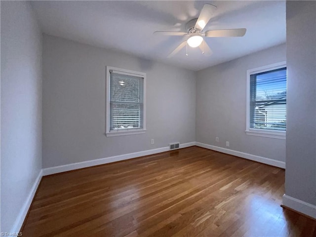 spare room with visible vents, ceiling fan, baseboards, and wood finished floors