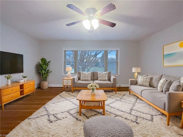 living room featuring ceiling fan, baseboards, and wood finished floors