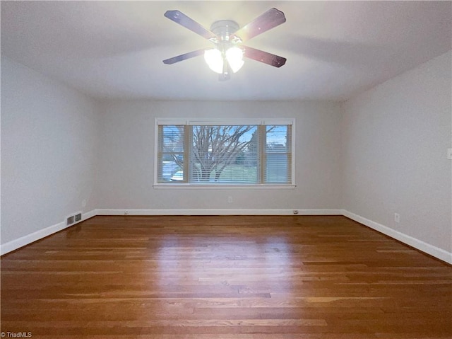 unfurnished room with a ceiling fan, visible vents, baseboards, and wood finished floors