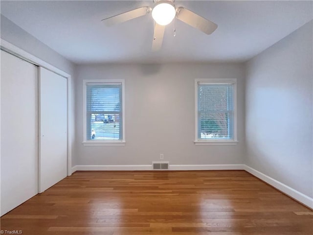 unfurnished bedroom with a closet, visible vents, baseboards, and wood finished floors