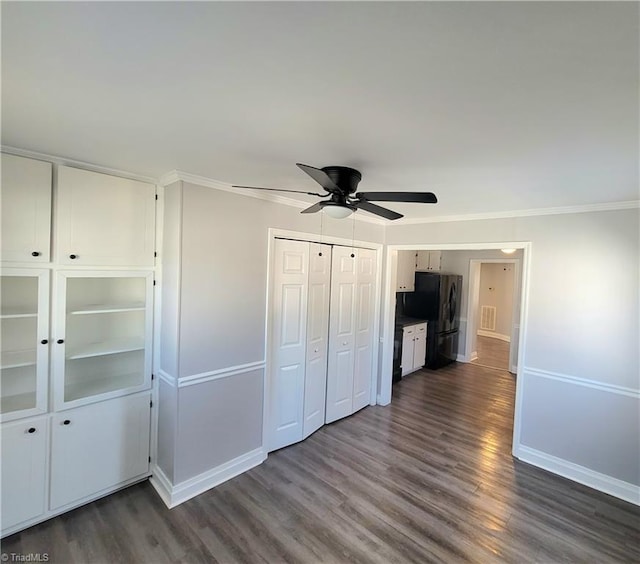 unfurnished bedroom featuring dark wood-type flooring, freestanding refrigerator, and baseboards