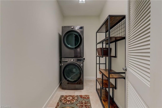 washroom featuring tile patterned floors, baseboards, stacked washer / drying machine, and laundry area