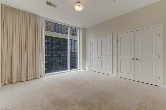 unfurnished bedroom with visible vents, carpet floors, and a closet