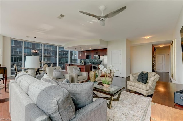 living room with ceiling fan, visible vents, and light wood-style flooring