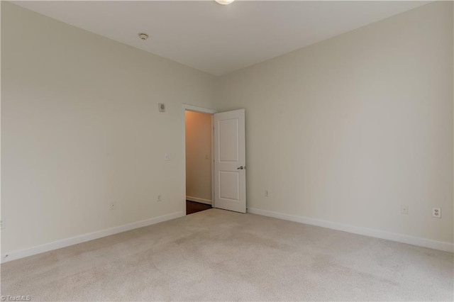 spare room featuring baseboards and light colored carpet