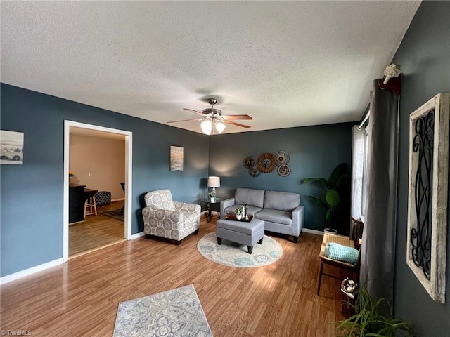 living room featuring hardwood / wood-style flooring, ceiling fan, and a textured ceiling