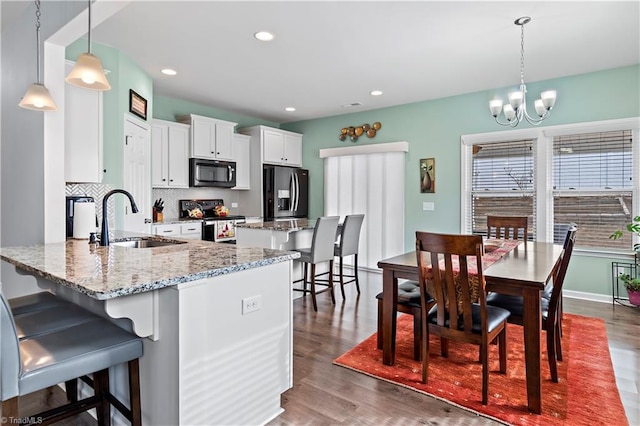 kitchen with hanging light fixtures, sink, white cabinets, and appliances with stainless steel finishes