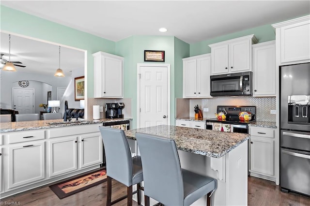 kitchen featuring pendant lighting, appliances with stainless steel finishes, a breakfast bar, and white cabinets