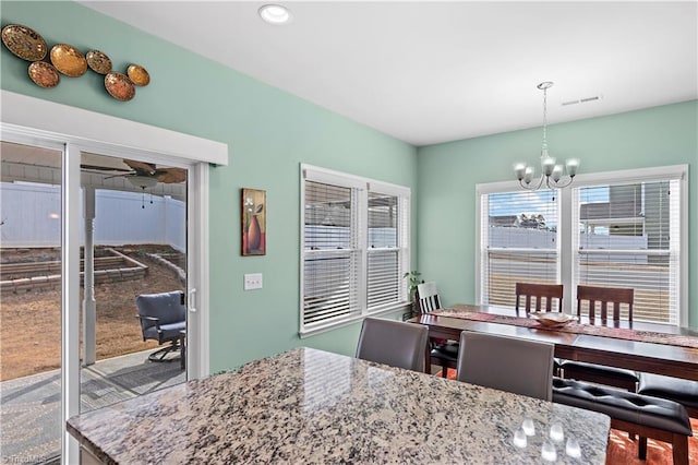 dining space with ceiling fan with notable chandelier