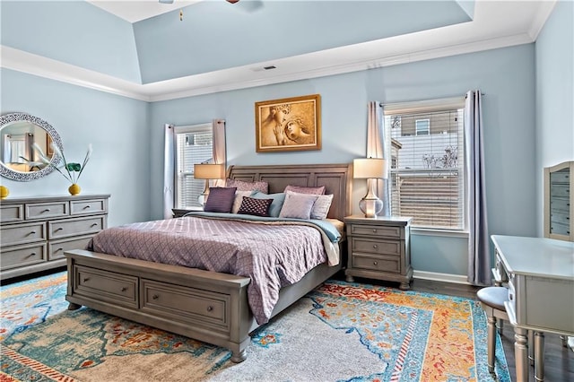 bedroom with a raised ceiling, ornamental molding, dark wood-type flooring, and ceiling fan