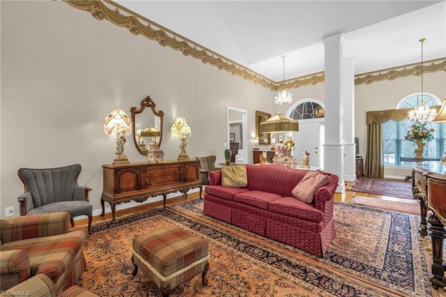 living room with high vaulted ceiling, an inviting chandelier, wood finished floors, and ornate columns