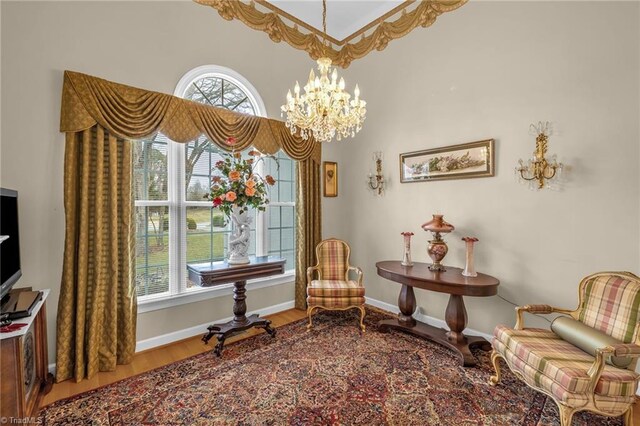 sitting room with a notable chandelier, baseboards, and wood finished floors