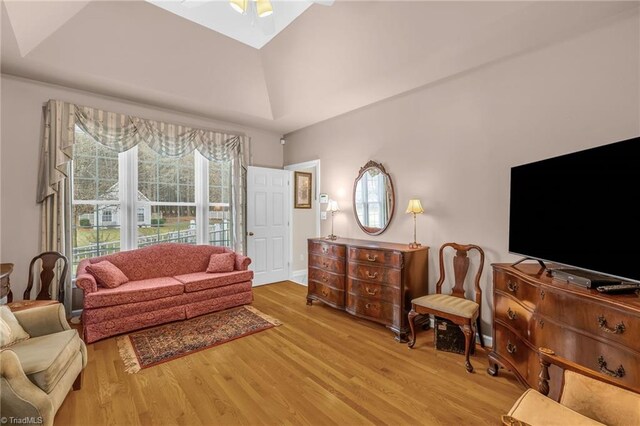 living area featuring ceiling fan, wood finished floors, and vaulted ceiling