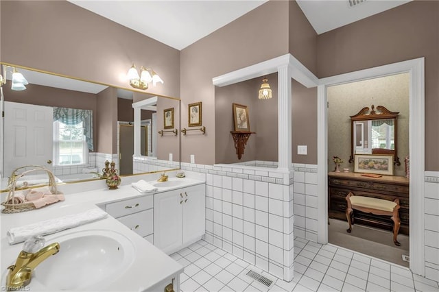 bathroom with tile patterned floors, tile walls, a wainscoted wall, and a sink