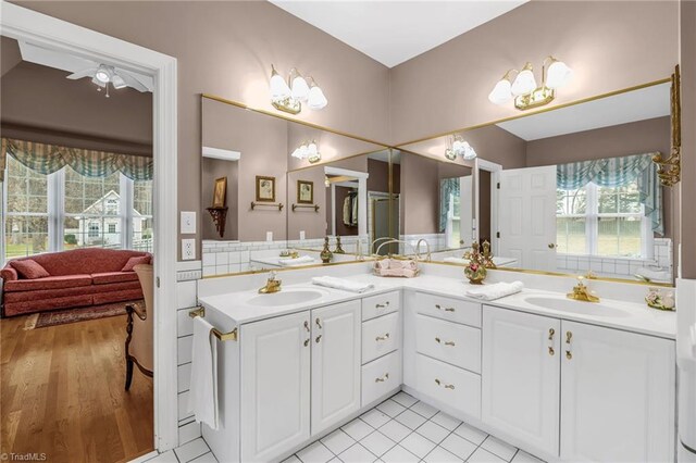 ensuite bathroom with ensuite bath, wood finished floors, double vanity, and a sink