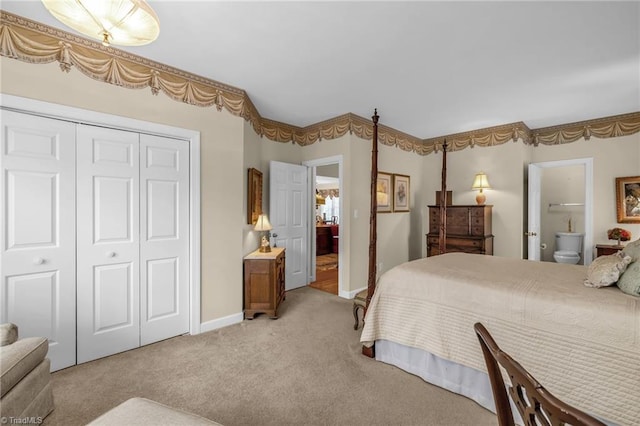 bedroom with a closet, light colored carpet, connected bathroom, and baseboards