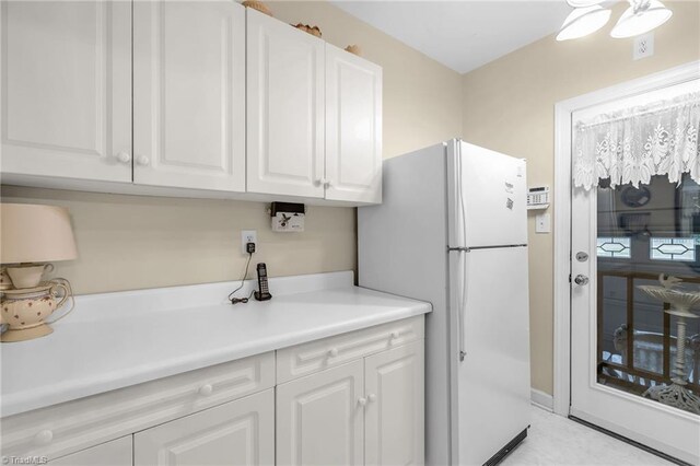 kitchen featuring white cabinets, light countertops, and freestanding refrigerator