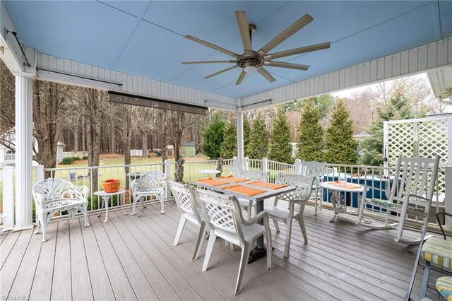 wooden deck with outdoor dining area and a ceiling fan