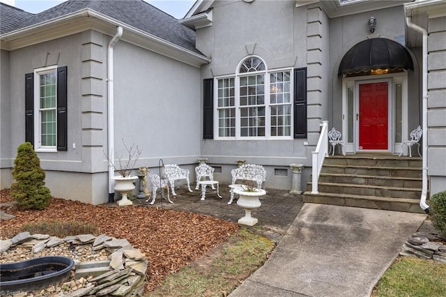 property entrance featuring crawl space, stucco siding, and a shingled roof