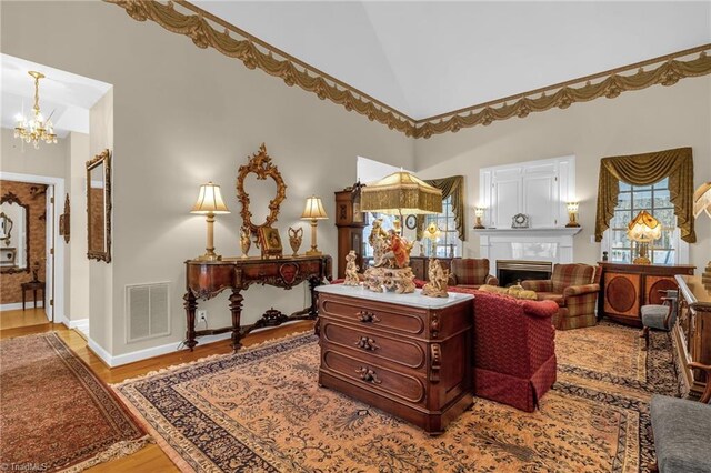 sitting room featuring visible vents, a fireplace, an inviting chandelier, wood finished floors, and high vaulted ceiling