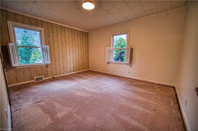 empty room with wallpapered walls, visible vents, ornamental molding, and baseboards