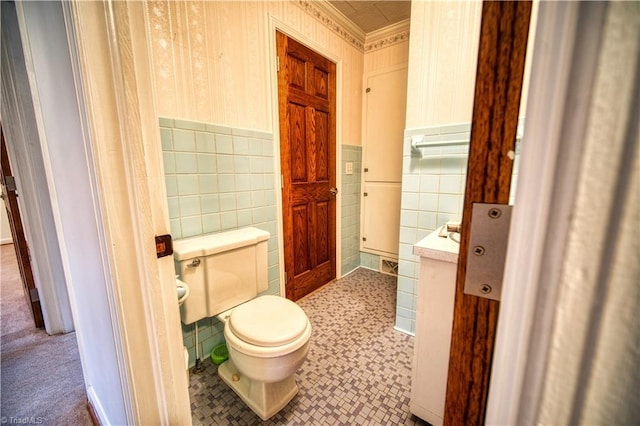 bathroom featuring toilet, a wainscoted wall, and tile walls