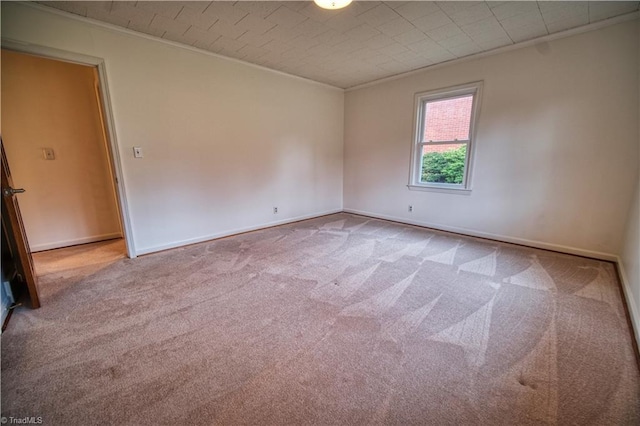 empty room featuring ornamental molding, carpet flooring, and baseboards