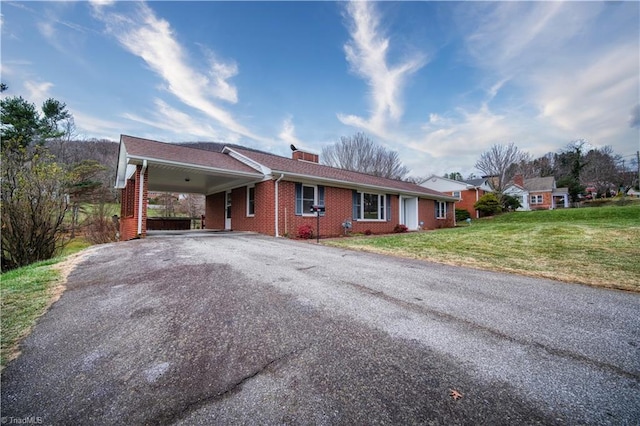 single story home featuring aphalt driveway, brick siding, a chimney, a front yard, and a carport