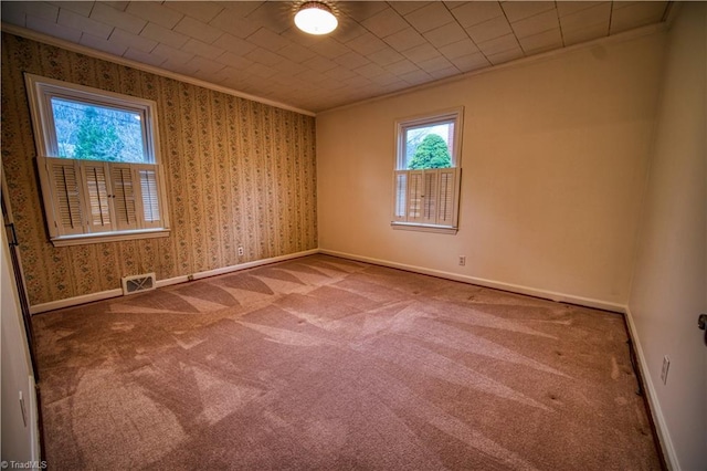 spare room featuring crown molding, baseboards, visible vents, and wallpapered walls