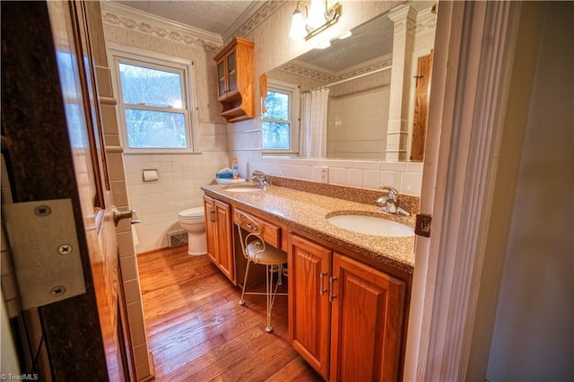 full bath featuring crown molding, a sink, tile walls, and wood finished floors