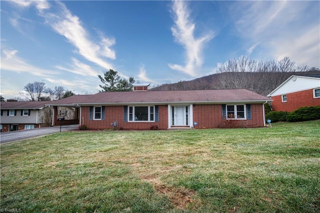 ranch-style house with brick siding, aphalt driveway, a carport, and a front yard