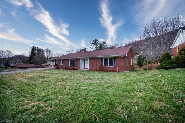 ranch-style house featuring a front lawn and brick siding