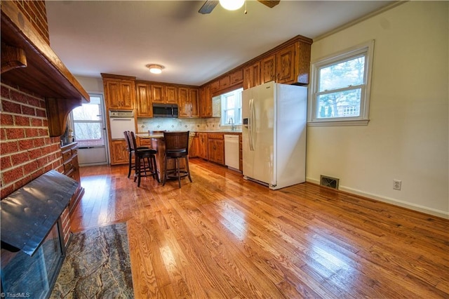 kitchen featuring brown cabinets, white appliances, a kitchen bar, and a center island