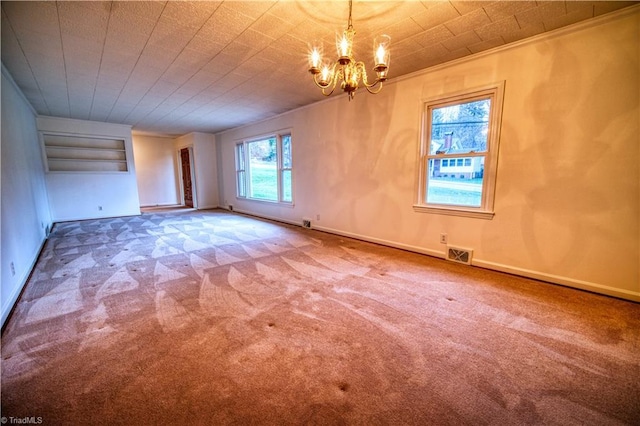 carpeted spare room featuring an inviting chandelier, baseboards, visible vents, and ornamental molding