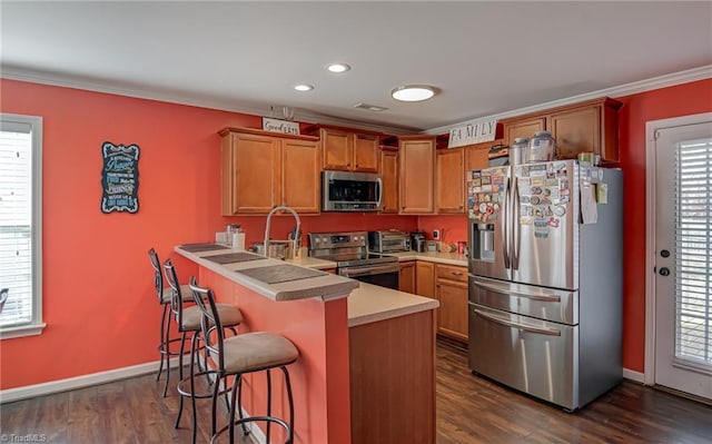 kitchen featuring a kitchen bar, appliances with stainless steel finishes, dark wood-type flooring, and kitchen peninsula