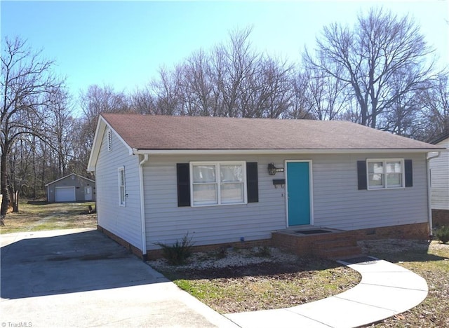 view of front of home with driveway, a detached garage, roof with shingles, crawl space, and an outdoor structure