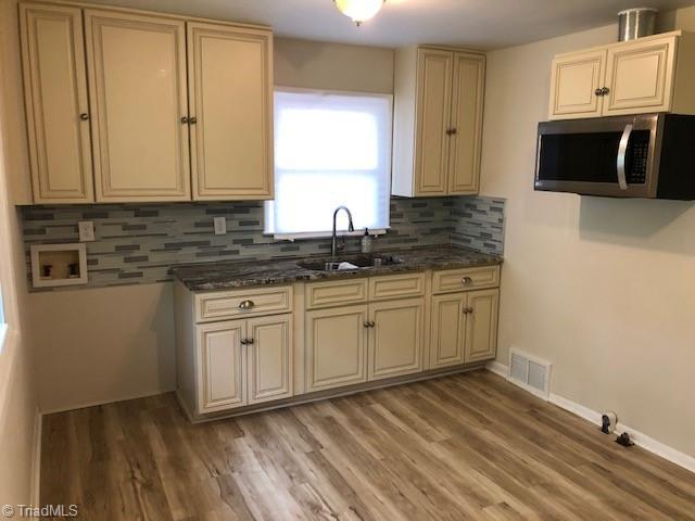 kitchen featuring stainless steel microwave, a sink, and cream cabinets