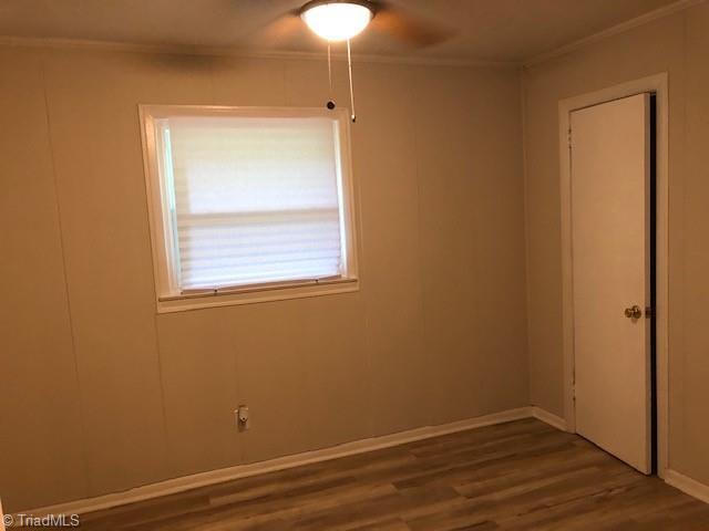 spare room with ornamental molding, wood finished floors, and baseboards