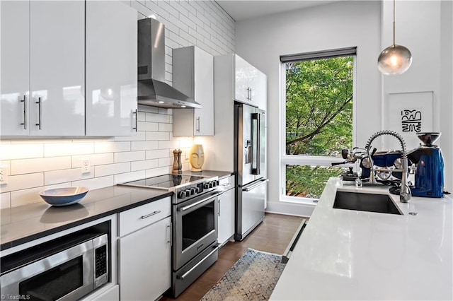 400 W 4th St Unit 305, Winston-Salem, NC 27101 - kitchen with wall chimney range hood, appliances with stainless steel finishes, tasteful backsplash, a sink, and hanging light fixtures