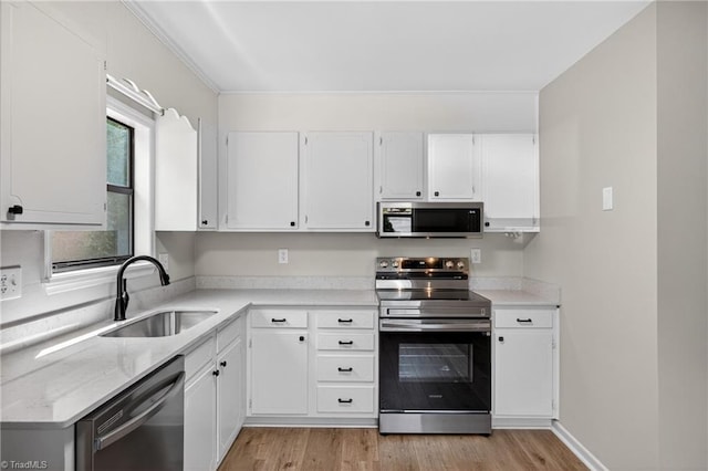 1814 Guyer St Unit A, High Point, NC 27265 - kitchen with stainless steel appliances, a sink, white cabinets, and light wood-style flooring