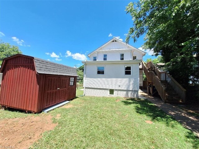 back of house featuring a storage unit and a lawn