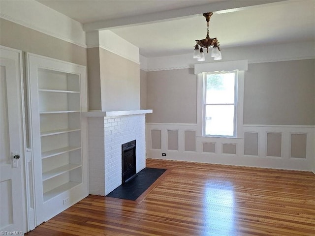 unfurnished living room featuring a chandelier, a brick fireplace, dark hardwood / wood-style floors, and built in features